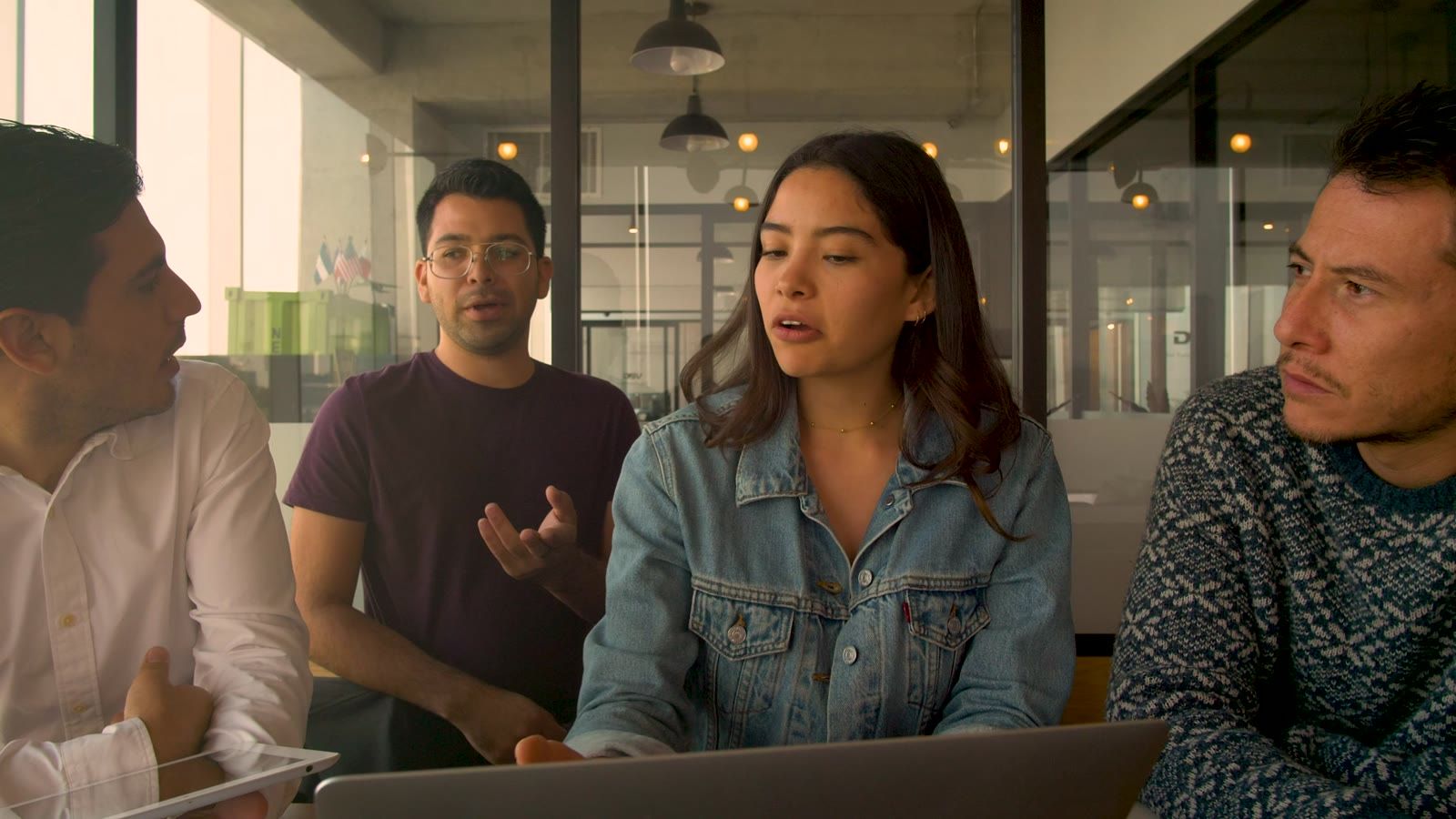 Four colleagues talking round a table with a laptop